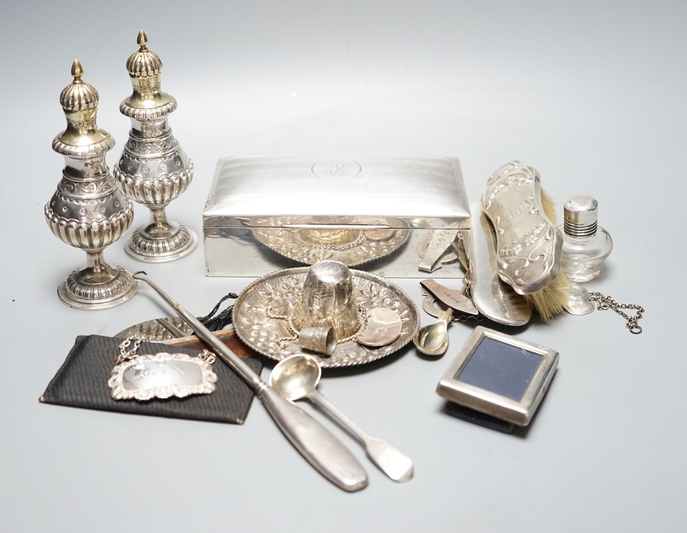 Assorted small silver including a cigarette box, pair of German 800 pepperettes, wine labels, spectacles case etc.
